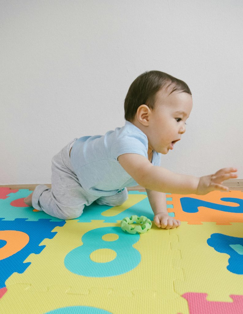 Adorable baby boy crawling on a vibrant puzzle mat indoors, showcasing childhood innocence and play.